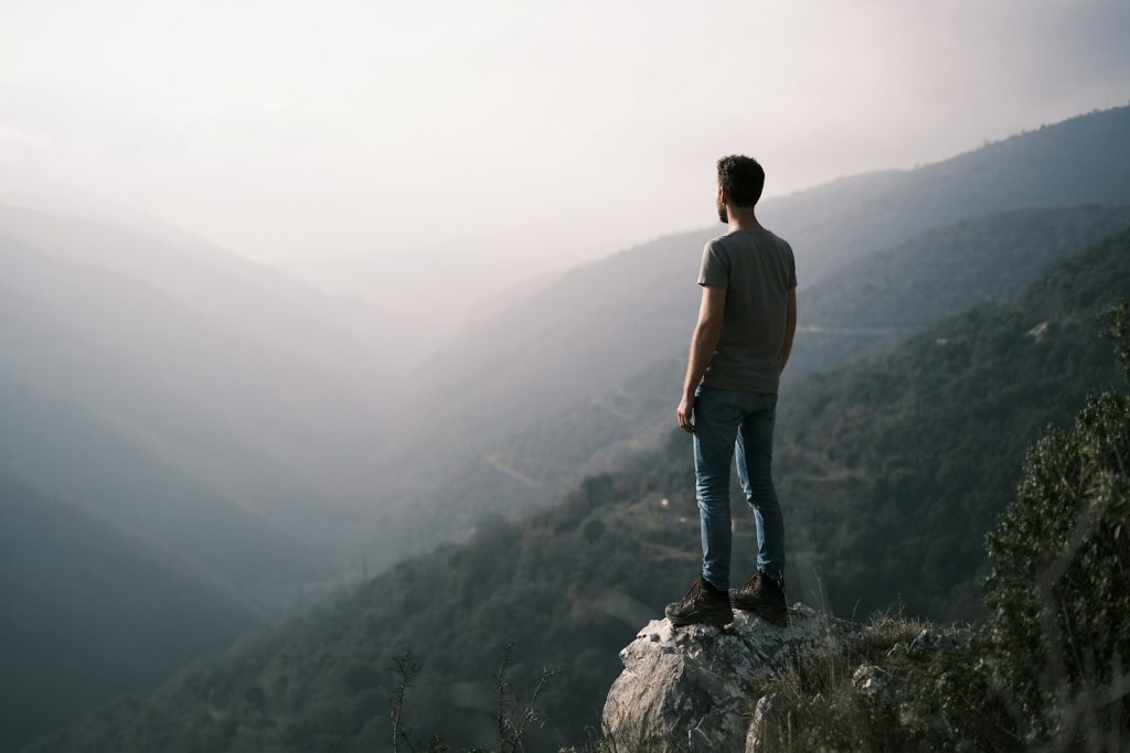 a man standing on top of a cliff overlooking a valley